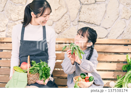 野菜を持ってベンチに座っている親子 137538174