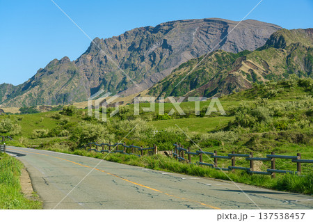 阿蘇の雄大な山並みと草原を走るドライブ風景 137538457