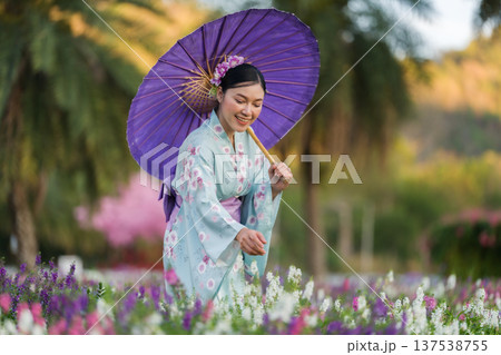 woman in yukata (kimono dress) holding umbrella with angelonia flower blooming in garden woman in yukata (kimono dress) holding umbrella with angelonia flower blooming in garden 137538755