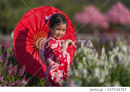 preschool child girl in yukata (kimono dress) holding umbrella with sakura flower or cherry blossom blooming in garden preschool child girl in yukata (kimono dress) holding umbrella with sakura flower or cherry blossom blooming in garden 137538787