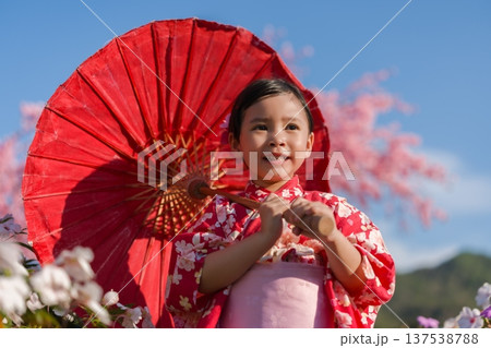 preschool child girl in yukata (kimono dress) holding umbrella with sakura flower or cherry blossom blooming in garden preschool child girl in yukata (kimono dress) holding umbrella with sakura flower or cherry blossom blooming in garden 137538788