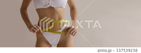 Sexy fitness diet banner with woman measuring slim waist with tape measure in white lingerie, weight loss and healthy lifestyle concept with copy space 137539238