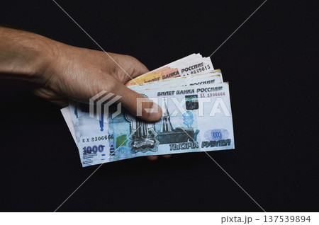 a pack of Russian rubles in a man's hand on a black background 137539894