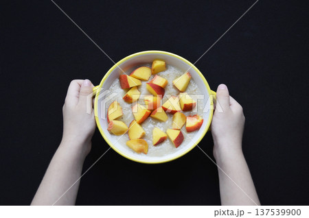 oatmeal cooked in milk with pieces of ripe peach in a bowl on a black background oatmeal cooked in milk with pieces of ripe peach in a bowl on a black background 137539900