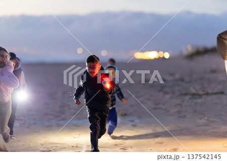 Kids running on beach at night with glowing light Kids running on beach at night with glowing light 137542145
