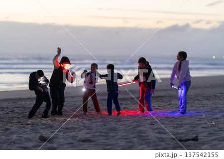Kids playing with colorful light sticks on beach at dusk 137542155