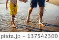 Father and child walking hand in hand on a wet sandy beach at sunset for family background and banner design 137542300