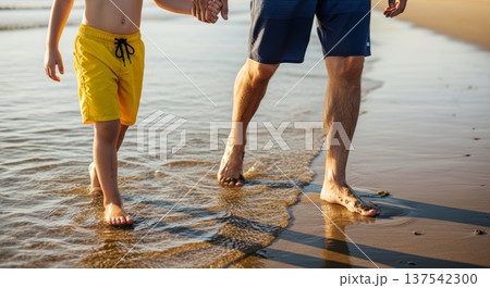 Father and child walking hand in hand on a wet sandy beach at sunset for family background and banner design 137542300