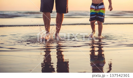 Father and child splashing water and walking in shallow sea at sunset for summer background and banner design 137542301