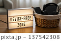Device free zone lightbox sign on wooden table with headphones and smartphone in wicker basket for home decor background and relaxation 137542308