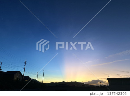 夕暮れの街並みと空に広がる光の筋 夕暮れの街並みと空に広がる光の筋 137542393