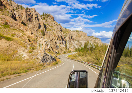 View from car of winding mountain highway. Beautiful autumn road connecting Novorossiysk and border with Mongolia. Freedom travel landscape Chuisky tract. Kurai. Altai Republic, Russia. View from car of winding mountain highway. Beautiful autumn road connecting Novorossiysk and border with Mongolia. Freedom travel landscape Chuisky tract. Kurai. Altai Republic, Russia. 137542413