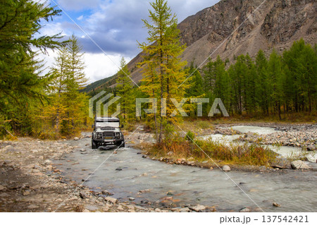 UAZ Hunter tourist SUV conquers a harsh mountain river Aktru flowing from glacier. Alpine camps and valley. Autumn sunny day. Landscape Mountains in Siberia. Chuiskiy Range, Altai Republic, Russia UAZ Hunter tourist SUV conquers a harsh mountain river Aktru flowing from glacier. Alpine camps and valley. Autumn sunny day. Landscape Mountains in Siberia. Chuiskiy Range, Altai Republic, Russia 137542421