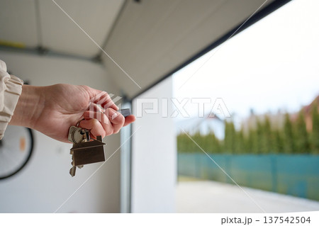 Hand holding keys near open garage door. Concept of home ownership 137542504