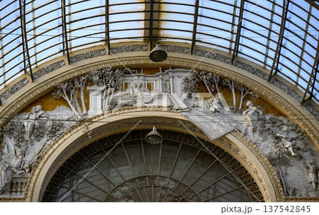 Interior detail of the Galleria Umberto I in Naples, Italy, featuring intricate architectural and decorative elements. The ornate frieze depicts classical figures and detailed trees in bas-relief. 137542845