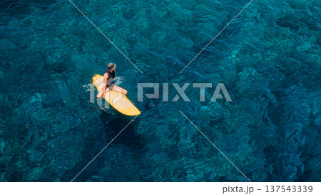Surfing concept. Woman on surfboard in blue sea. Drone view 137543339