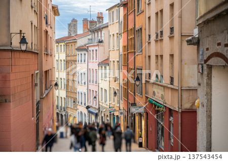 Lyon, france. December 28, 2023. Pedestrians walking down a narrow cobblestone street in lyon, france, with historical architecture and vibrant facades Lyon, france. December 28, 2023. Pedestrians walking down a narrow cobblestone street in lyon, france, with historical architecture and vibrant facades 137543454