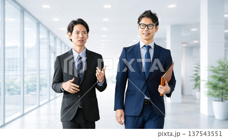 話しながら歩く2人の男性ビジネスマン 話しながら歩く2人の男性ビジネスマン 137543551