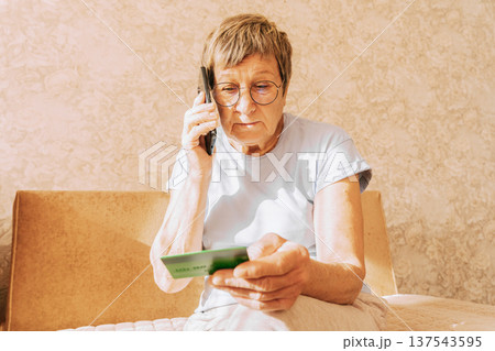 A naive elderly woman gives her bank card details to telephone scammers. Financial fraud using personal information, manipulation, criminal activity A naive elderly woman gives her bank card details to telephone scammers. Financial fraud using personal information, manipulation, criminal activity 137543595