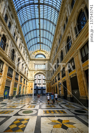 Galleria Umberto I in Naples, Italy features an elegant glass-domed arcade. The floor showcases intricate geometric patterns with marble tiles in white, green, and yellow. 137543741