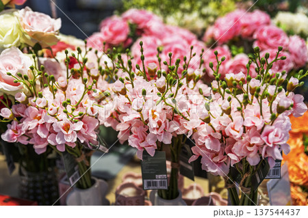 Artificial pink cherry blossom bouquets in vases on a store shelf. 137544437