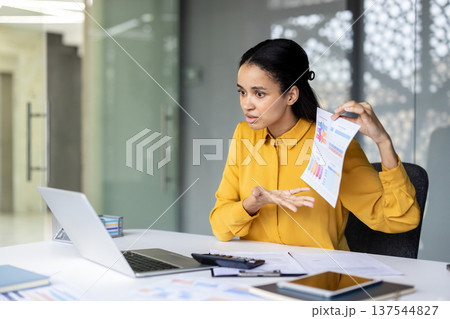 Successful businesswoman presenting financial charts during a video conference, discussing project results and data analysis with colleagues remotely on a laptop in a modern office workplace Successful businesswoman presenting financial charts during a video conference, discussing project results and data analysis with colleagues remotely on a laptop in a modern office workplace 137544827