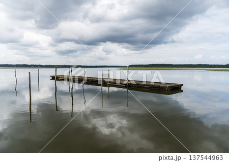 Lake of Soustons reflecting a cloudy sky and wooden docks Lake of Soustons reflecting a cloudy sky and wooden docks 137544963