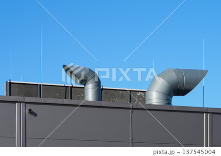 Industrial Ventilation Pipes, Air Exhaust Ducts and lightning rods on Factory Roof Under Blue Sky Industrial Ventilation Pipes, Air Exhaust Ducts and lightning rods on Factory Roof Under Blue Sky 137545004