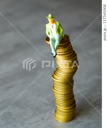 Miniature businessman sitting and balancing on a pile of coins, wealth and investment concept Miniature businessman sitting and balancing on a pile of coins, wealth and investment concept 137545008