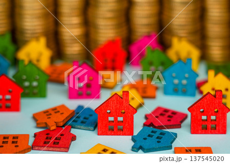 Colorful Wooden Houses in Front of Gold Coin Stacks Real Estate Investment Concept 137545020