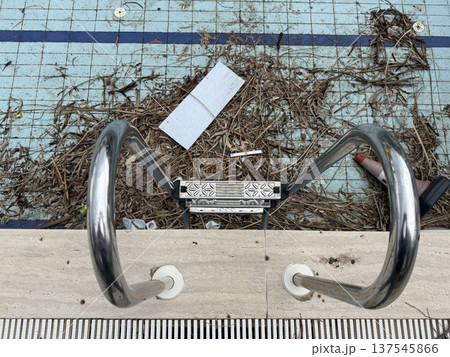 Empty pool with dry leaves and debris, stainless steel handrails, and neglect concept 137545866