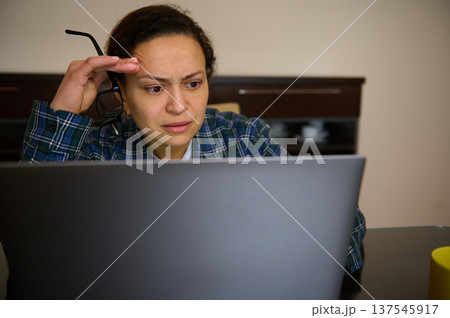 Woman Entrepreneur Working From Home On Laptop Looking Concerned While Telecommuting Woman Entrepreneur Working From Home On Laptop Looking Concerned While Telecommuting 137545917