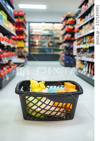 Shopping basket filled with groceries in supermarket aisle Shopping basket filled with groceries in supermarket aisle 137545991