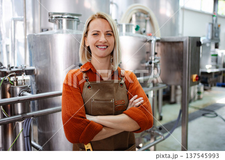 Woman brewmaster standing in craft beer brewery with arms crossed Woman brewmaster standing in craft beer brewery with arms crossed 137545993