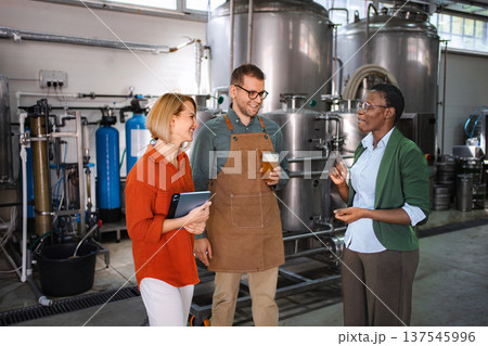 Diverse business team discussing craft beer production in a brewery Diverse business team discussing craft beer production in a brewery 137545996