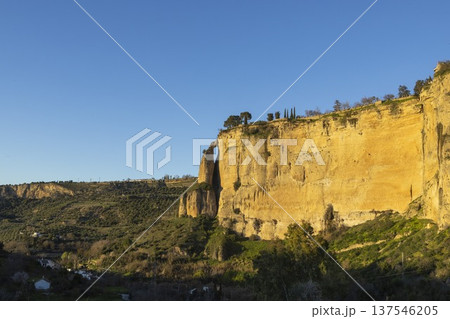 Visit popular Ronda in Spain as the sun sets over the mountains and cliffs near the town 137546205