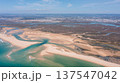 Drone captures the landscape of Ria Formosa and Praia de Faro in Portugal showing sandy beaches, water, and green areas under clear blue skies 137547042