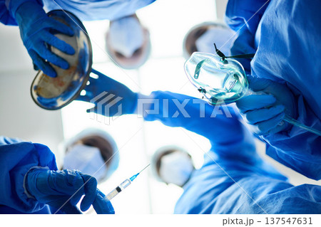 Surgery team, below and a doctors in a hospital or theatre to start operation with anesthesia. Surgeon, assistant and medical group together for emergency healthcare with a oxygen mask and syringe 137547631