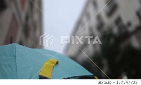Urban rainy day scene with teal umbrella and city buildings. Horizontal banner. Copy space Urban rainy day scene with teal umbrella and city buildings. Horizontal banner. Copy space 137547735