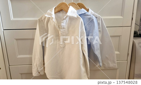 Classic children's fashion - white and blue shirts hanging for stylish kids' outfits Classic children's fashion - white and blue shirts hanging for stylish kids' outfits 137548028