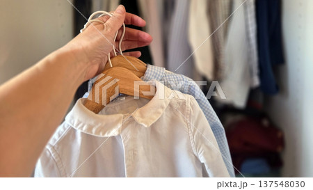 Organizing children's wardrobe with neatly hanged shirts in closet Organizing children's wardrobe with neatly hanged shirts in closet 137548030