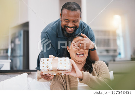 Birthday gift surprise, cover eyes and couple smile, woman and black man giving package for love, anniversary or gratitude. Living room couch, marriage and home people happy for present box Birthday gift surprise, cover eyes and couple smile, woman and black man giving package for love, anniversary or gratitude. Living room couch, marriage and home people happy for present box 137548455