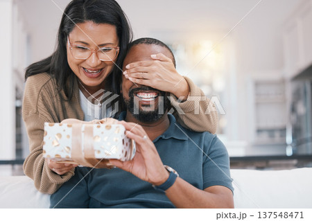 Birthday gift surprise, cover eyes and happy couple giving Christmas package for love, congratulations or gratitude. Lounge sofa, support care and home man, woman or people celebrate with present box Birthday gift surprise, cover eyes and happy couple giving Christmas package for love, congratulations or gratitude. Lounge sofa, support care and home man, woman or people celebrate with present box 137548471