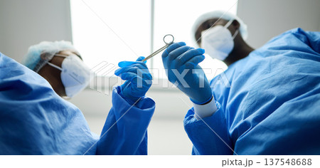 Surgery team, scissors and a doctor in a hospital or theatre to start operation with surgical tools. Below a surgeon and assistant with sterile equipment for medical procedure or emergency healthcare 137548688