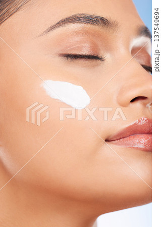 Face makeup, cream and studio woman with skin cosmetics, anti aging glow and closeup facial hydration creme. Collagen product application, acne prevention or model with eyes closed on blue background Face makeup, cream and studio woman with skin cosmetics, anti aging glow and closeup facial hydration creme. Collagen product application, acne prevention or model with eyes closed on blue background 137549694