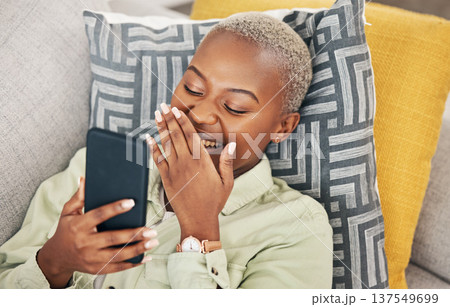 Black woman on sofa with phone, laughing and meme on social media, message or video online. Happy face, smile and internet, girl on couch with digital app on smartphone and funny viral post in home. Black woman on sofa with phone, laughing and meme on social media, message or video online. Happy face, smile and internet, girl on couch with digital app on smartphone and funny viral post in home. 137549699