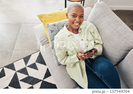 Woman, portrait and relax with phone on couch for social media, text chat and contact at home from above. Happy african person, smartphone and download mobile games, digital multimedia and dating app Woman, portrait and relax with phone on couch for social media, text chat and contact at home from above. Happy african person, smartphone and download mobile games, digital multimedia and dating app 137549704