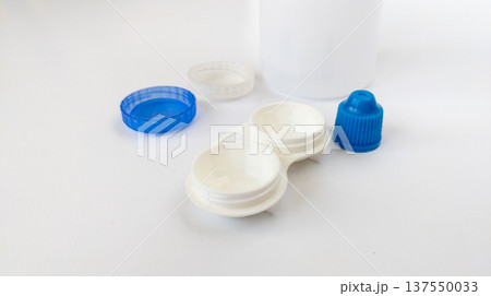 Plastic case for storing contact lenses, bottle with lens solution on white. Wearing contact lenses due to poor, blurred vision, and nearsightedness. 137550033