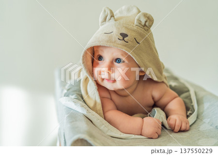 Baby lying on a changing table wrapped in a soft towel after bathing at home. Clean, calm and cozy moment of infant care and safety. Baby hygiene, daily routine and gentle parenting concept Baby lying on a changing table wrapped in a soft towel after bathing at home. Clean, calm and cozy moment of infant care and safety. Baby hygiene, daily routine and gentle parenting concept 137550229