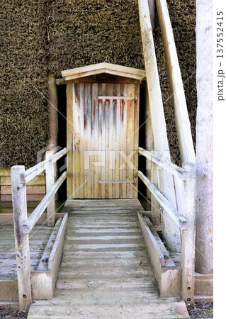 A wooden door and ramp against a wall of cooling tower branches A wooden door and ramp against a wall of cooling tower branches 137552415